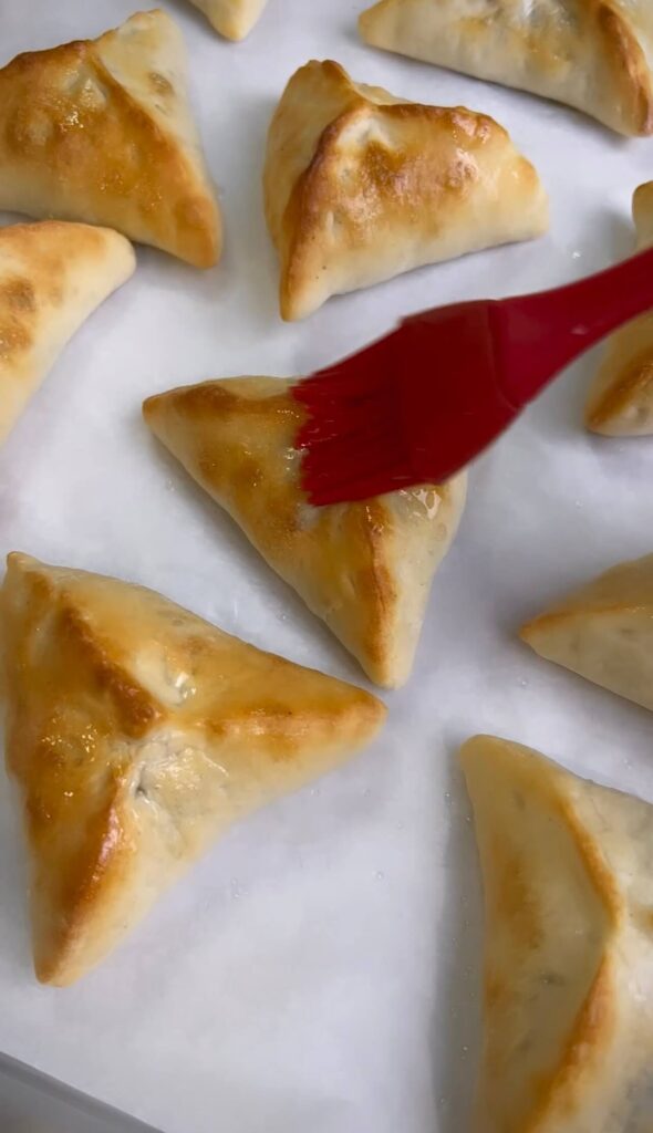  Brushing the freshly baked pies with a bit of extra oil for a glossy and flavorful finish.Si