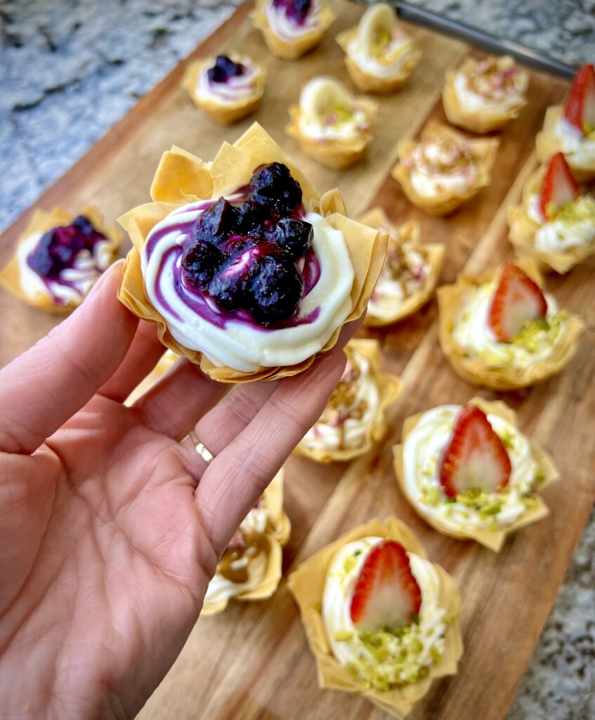 Baklava cheesecake bites topped with fresh raspberries, adding a burst of color and flavor to the creamy dessert.
