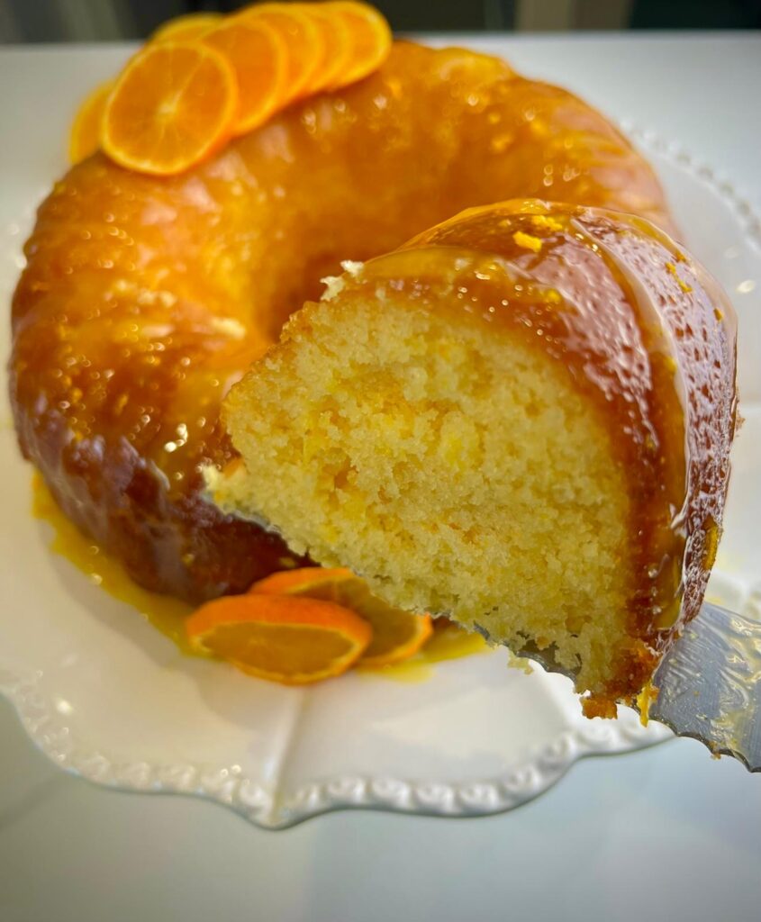 Slice of moist orange cake with a vibrant orange glaze, showcasing its soft texture.