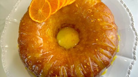 Orange cake with a glossy orange glaze on top, garnished with fresh citrus zest.