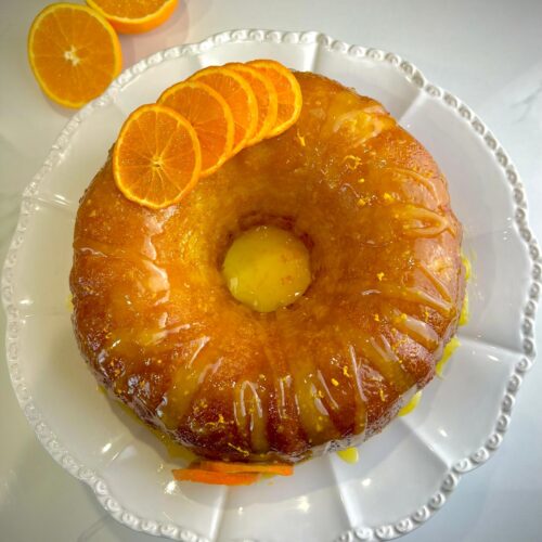 Orange cake with a glossy orange glaze on top, garnished with fresh citrus zest.