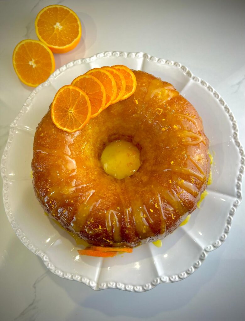 Orange cake with a glossy orange glaze on top, garnished with fresh citrus zest.