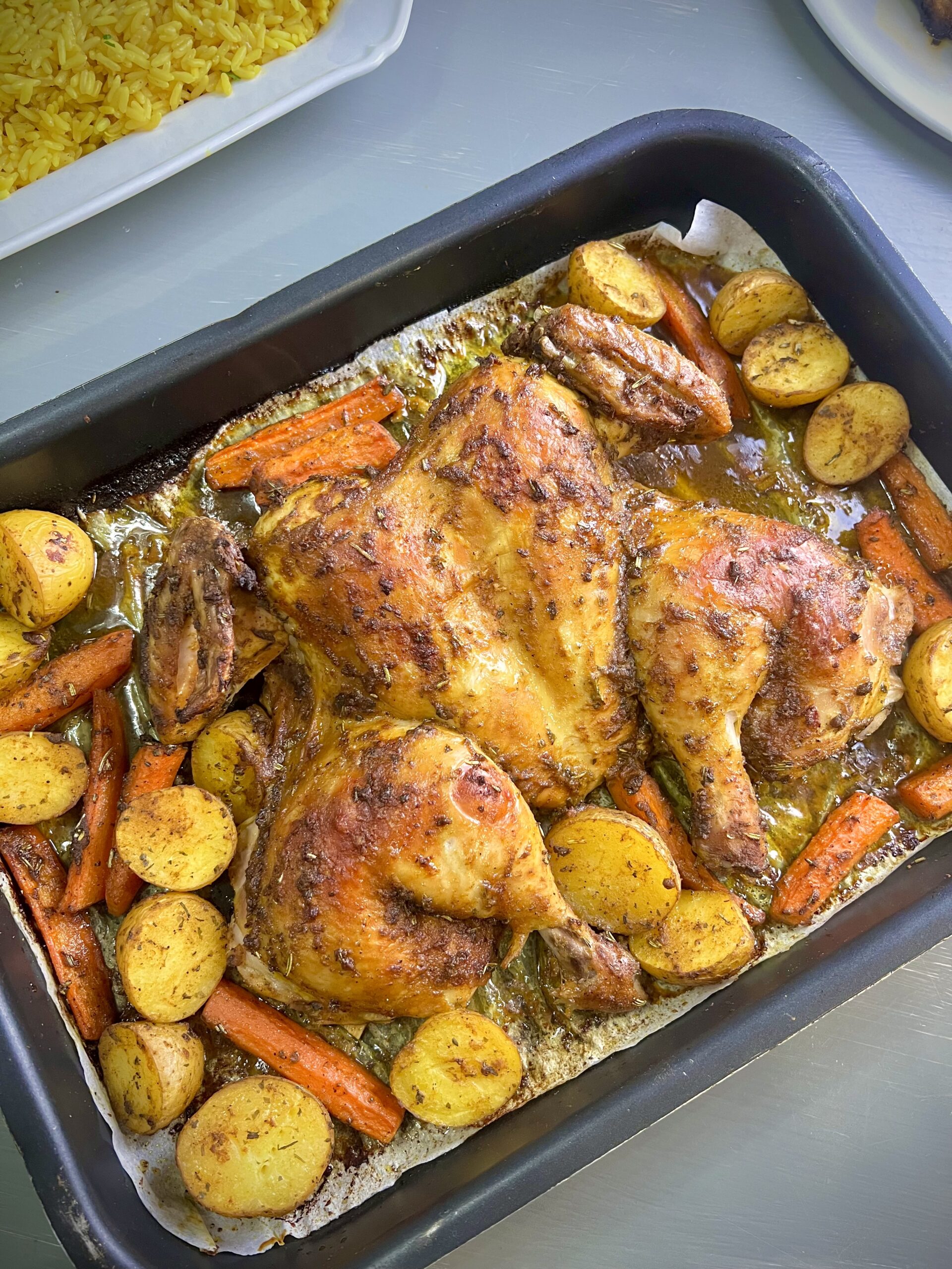 Golden, crispy roasted chicken flattened for even cooking, surrounded by perfectly caramelized potatoes and carrots, seasoned with a blend of aromatic spices and herbs. A mouthwatering one-pan dinner ready to impress!