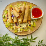 Fresh vegetable spring rolls filled with colorful vegetables, served with a side of dipping sauce.”