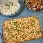 A tray featuring creamy chicken casserole, a vibrant green salad, and a serving of fluffy white rice, arranged neatly for a balanced and delicious meal