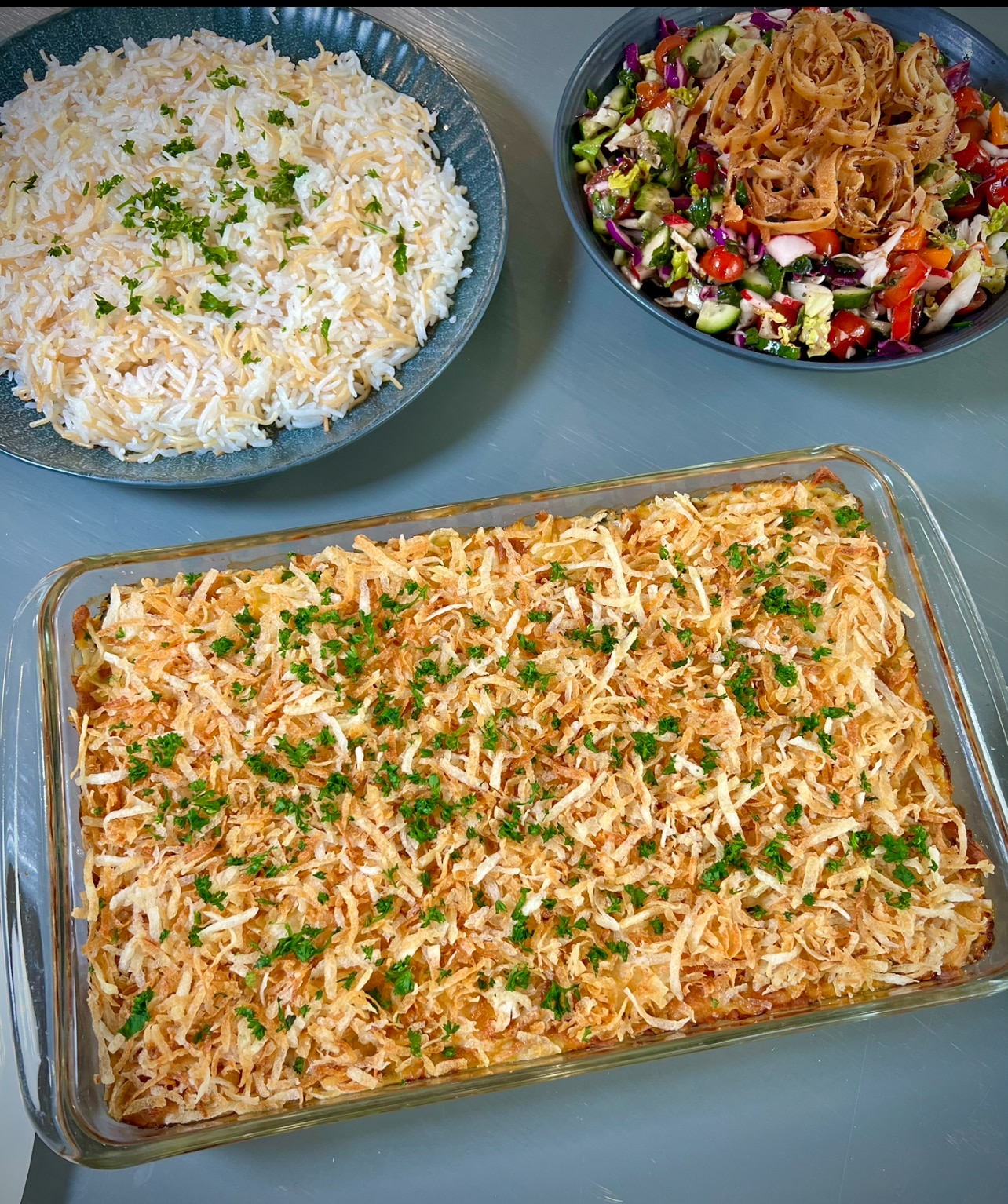 A tray featuring creamy chicken casserole, a vibrant green salad, and a serving of fluffy white rice, arranged neatly for a balanced and delicious meal