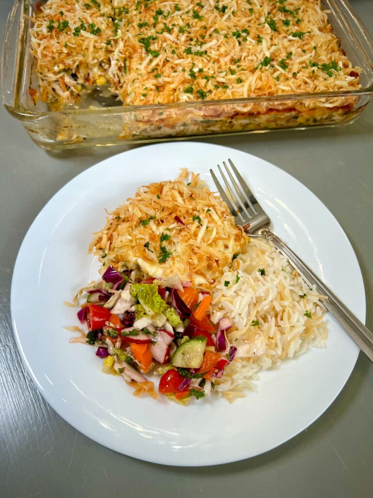 Delicious chicken casserole served with a side of fluffy rice and a fresh green salad, creating a well-balanced and hearty meal.