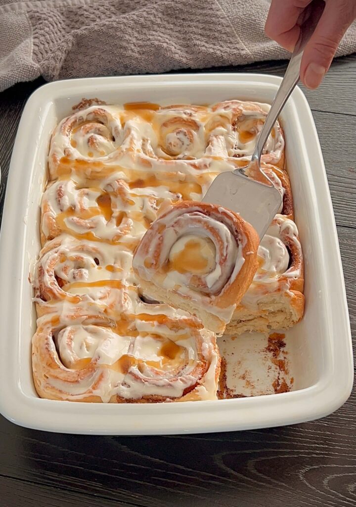 Freshly baked cinnamon rolls drizzled with icing on a plate.