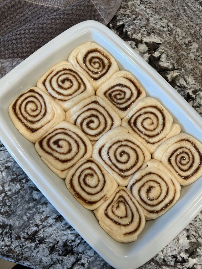 Unbaked cinnamon rolls arranged in a pan, ready to be baked.