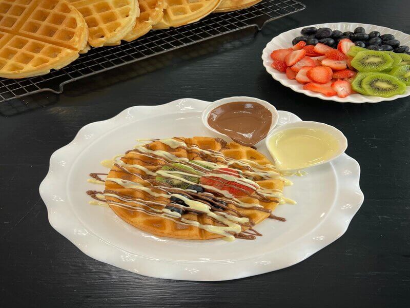 Pancake topped with chocolate, whipped cream, blueberries, strawberries, and kiwi.