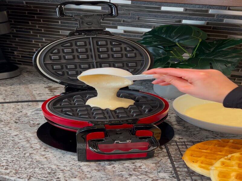 Pouring waffle batter into the waffle pan.
