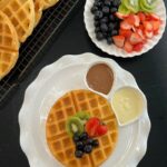 Crispy waffle topped with fresh blueberries, kiwi, chocolate sauce, and whipped cream.