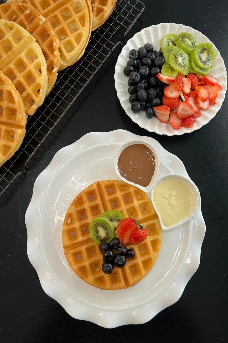 Crispy waffle topped with fresh blueberries, kiwi, chocolate sauce, and whipped cream.