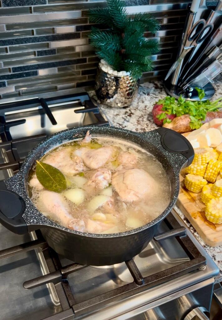 Tender chicken boiling in a golden broth with aromatics, preparing for a hearty dish.