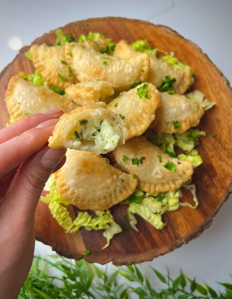 A plate of golden, crispy fried cheese sambousek, served hot with a side of yogurt or tahini sauce for dipping.