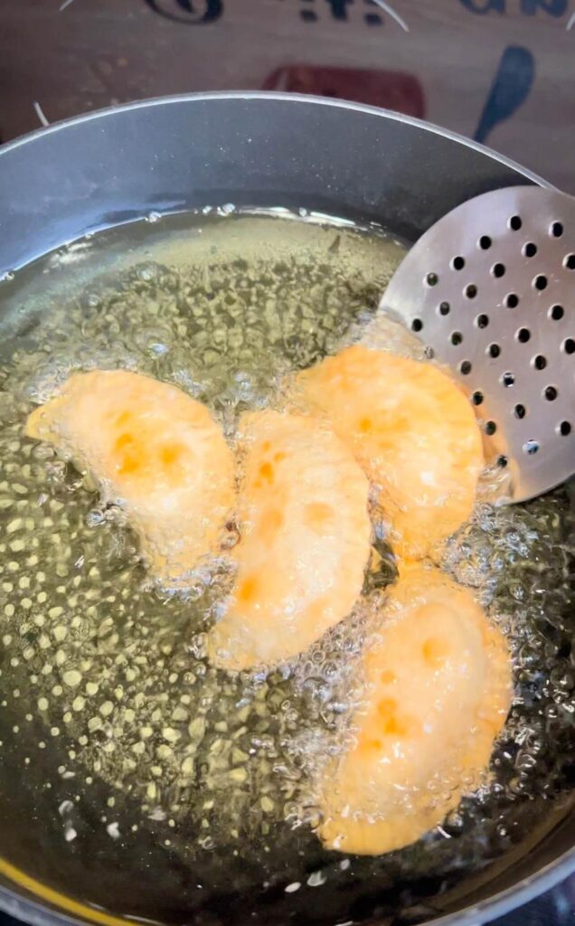 A plate of golden, crispy fried cheese sambousek, served hot with a side of yogurt or tahini sauce for dipping.