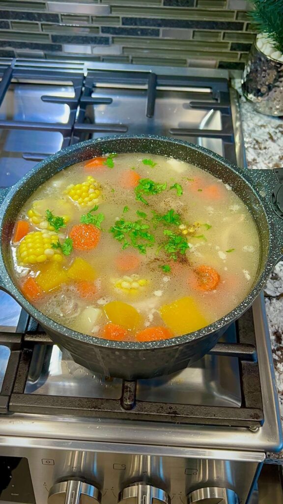 A pot filled with diced potatoes, plantains, and yuca, ready to be cooked in the flavorful chicken broth.

