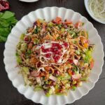 A vibrant Middle Eastern Fattoush salad with fresh vegetables, crispy pita bread, and a tangy dressing, garnished with herbs and pomegranate seeds.