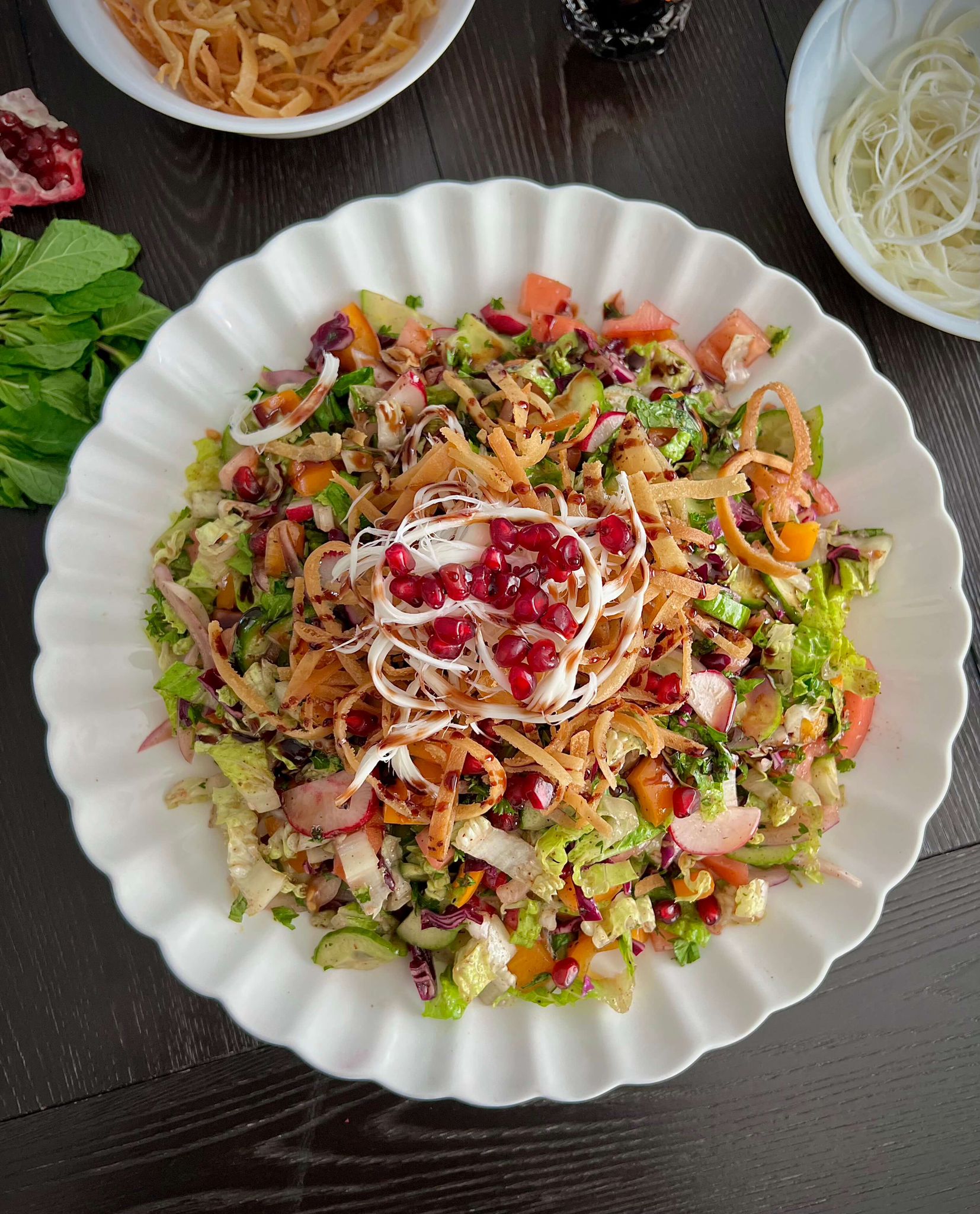 A vibrant Middle Eastern Fattoush salad with fresh vegetables, crispy pita bread, and a tangy dressing, garnished with herbs and pomegranate seeds.