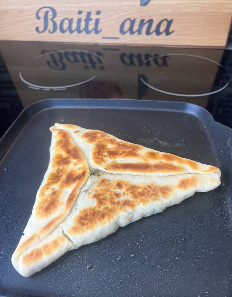 Cooking Saj spinach fatayer in the pan on top the stove