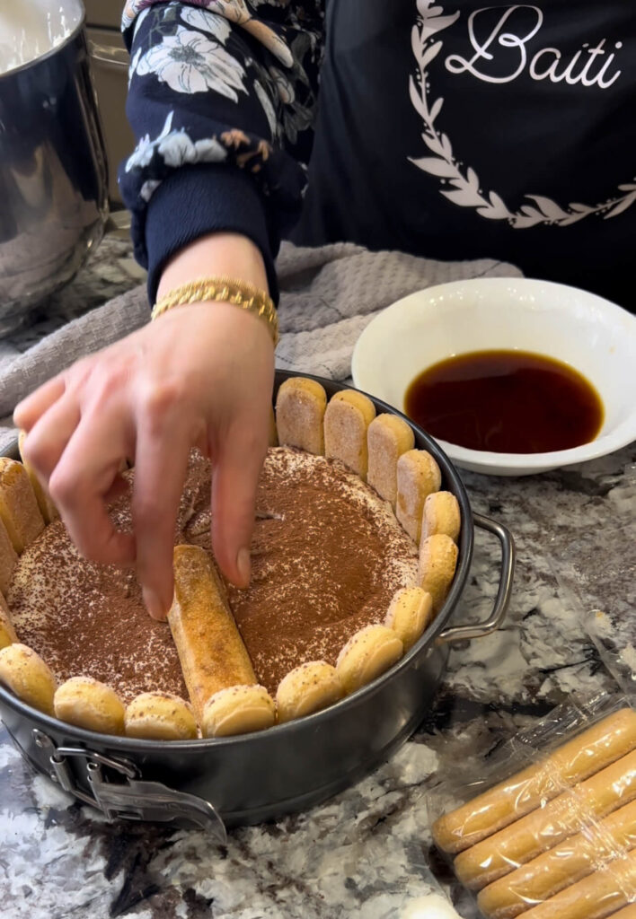 Layering the lady fingers and the cream to make tiramisu