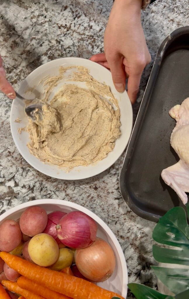 Mixing softened butter with herbs and garlic to spread all over the roast chicken 