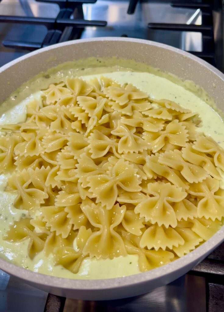 Mixing the creamy pesto sauce with the pasta