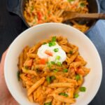 Serving taco pasta with sour cream on top