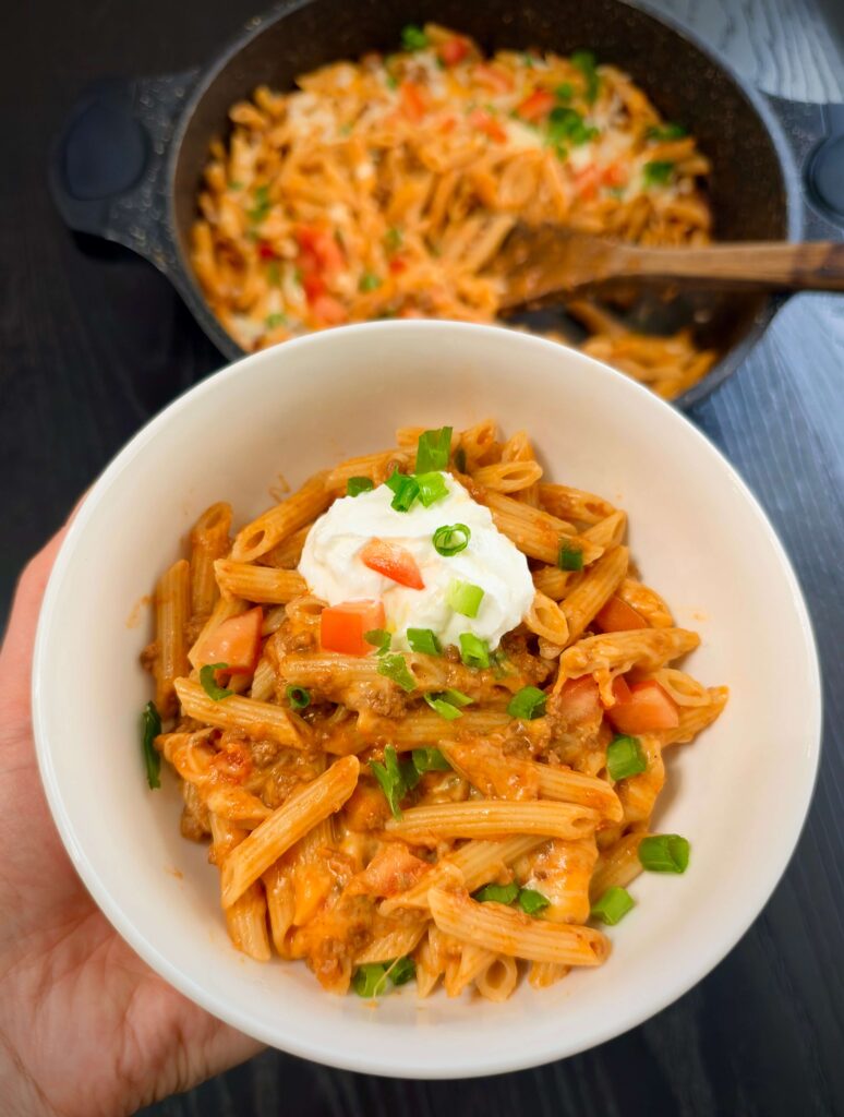 Serving taco pasta with sour cream on top