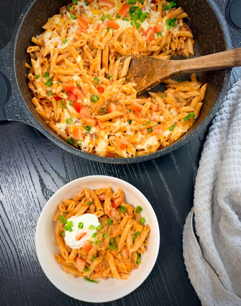 Serving One-Pan Taco Pasta with sour cream on top