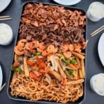 Hibachi style dinner made with all three proteins chicken meat and shrimp served with noodles and white rice