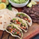 Serving steak tacos in a warm tortilla with guacamole and pico de gallo and squeeze of lime