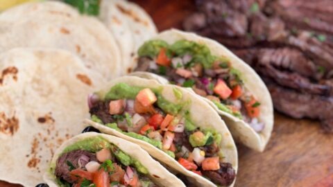 Serving steak tacos in a warm tortilla with guacamole and pico de gallo and squeeze of lime